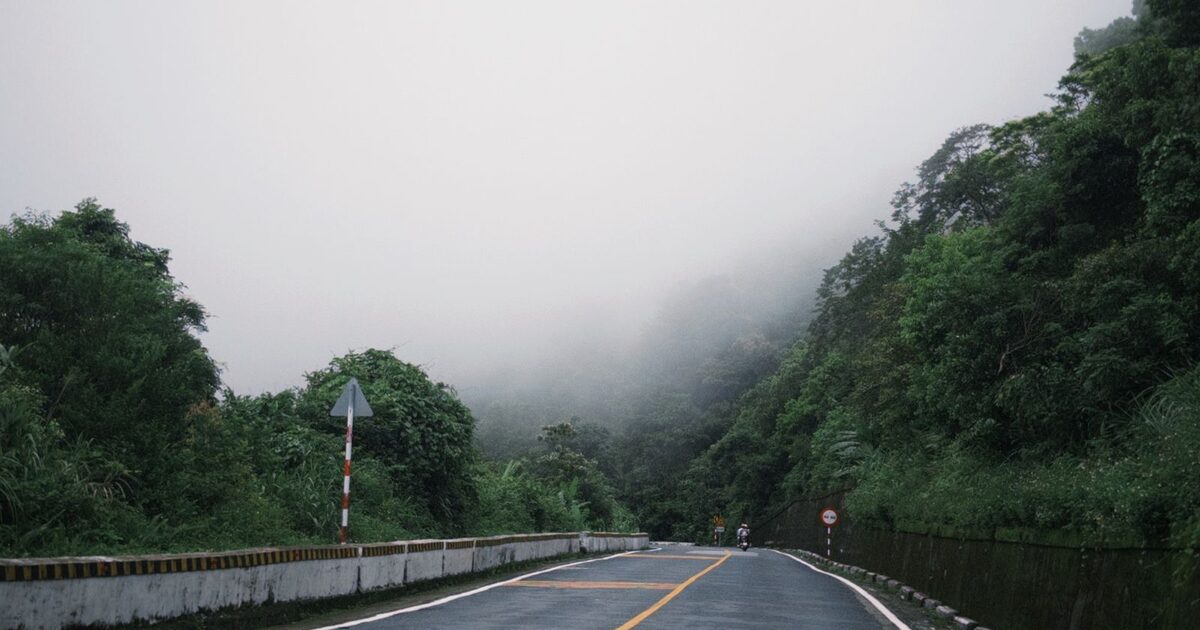 A mountain road disappearing into thick fog — a path that's there but unseen