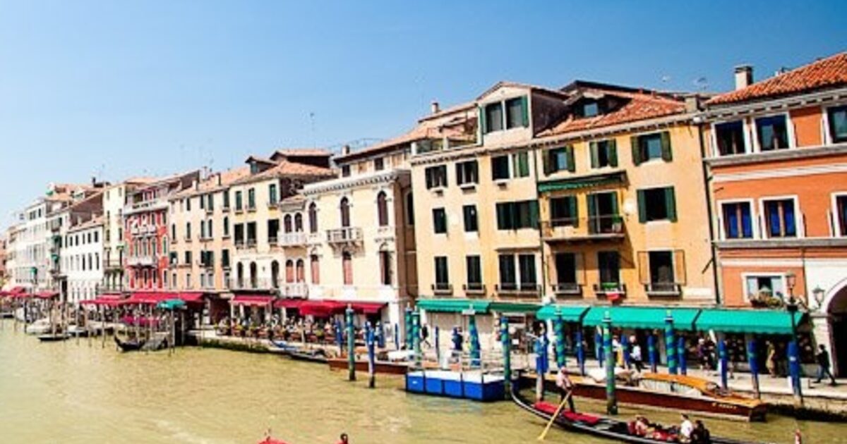 A row of Venice canal-front buildings, similar at a glance but each one a different color, height and shape up close